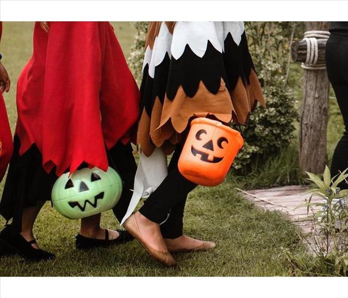 Kids dressed in their Halloween costumes, with their pumpkin baskets to be filled with candy.